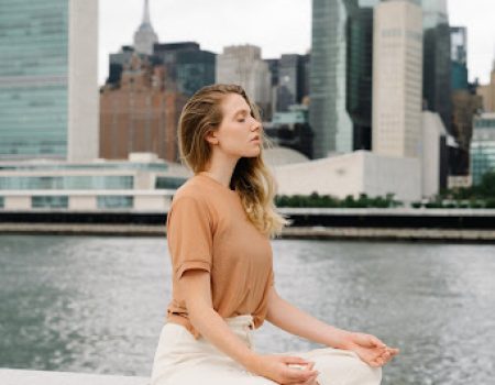 woman demonstrating her spirituality by meditating on wall with view of New York City in the back